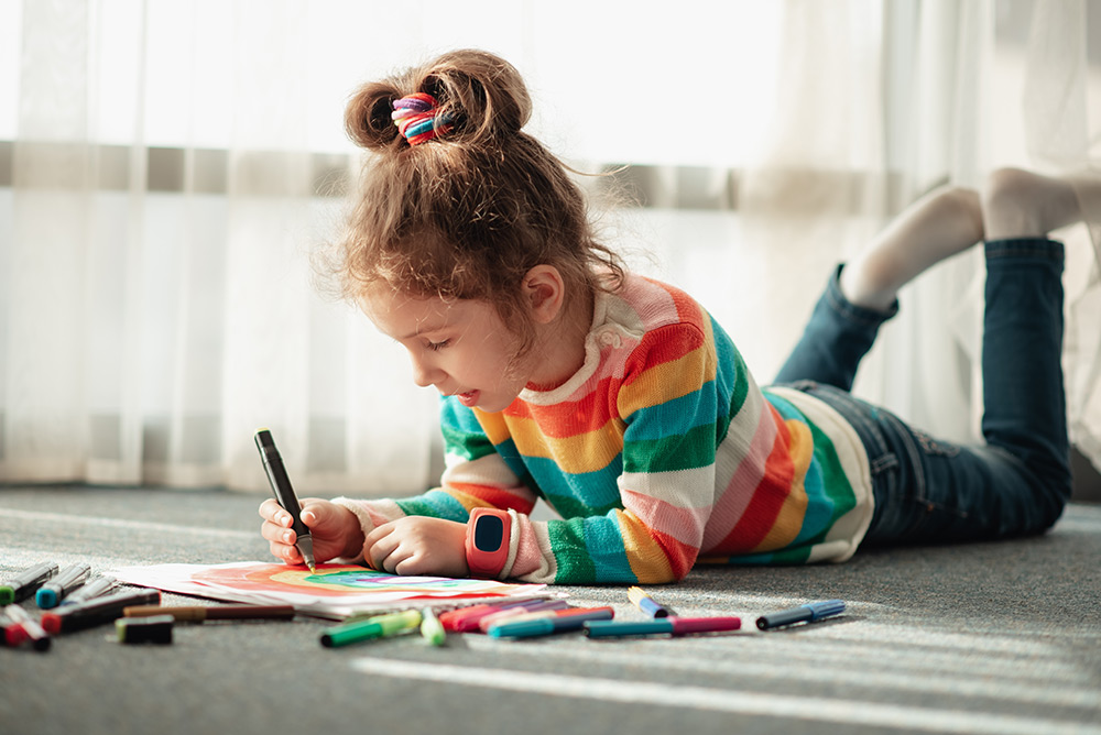 Young girl laying on the floor colouring